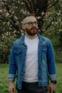 Portrait of young man standing against trees