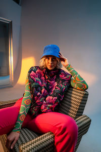 Confident blonde woman wearing trendy clothes sitting at studio and looking at the camera.