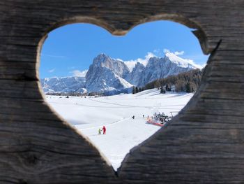Scenic view of snowcapped mountains seen through heart shape wooden fence