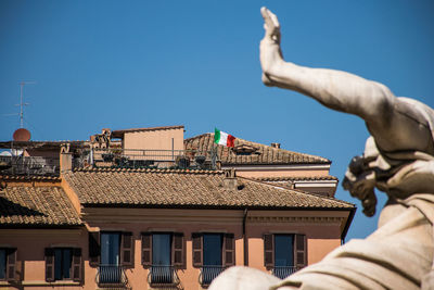 Low section of man and building roof against clear sky