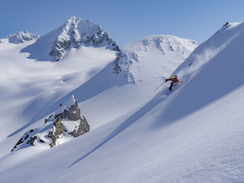 Low angle view of man skiing on snowcapped mountain against sky