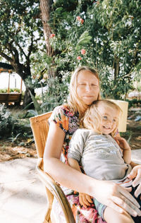 Portrait of smiling grandmother sitting with granddaughter on chair