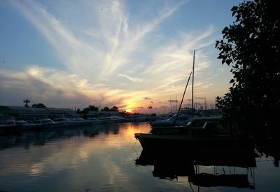 Sailboats moored at harbor during sunset