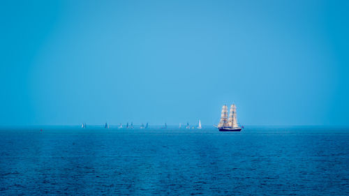 Sailboat sailing on sea against clear blue sky