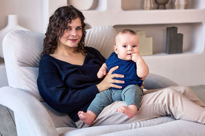 Portrait of mother with baby sitting at home