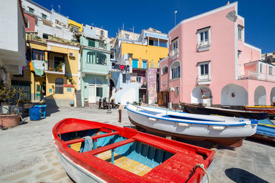 Boats moored in canal by buildings against sky