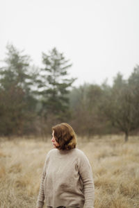 Woman standing by forest in foggy weather