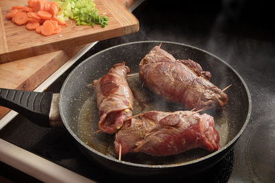 Close-up of meat in cooking pan on stove