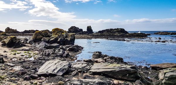 Rock formation on beach against sky