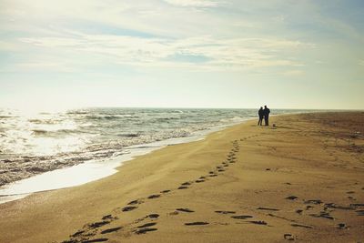 Couple standing on beach against sky