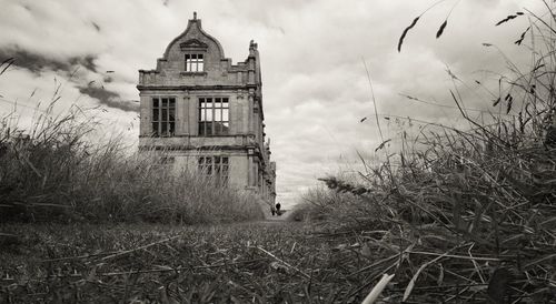 Low angle view of abandoned old mansion against cloudy sky