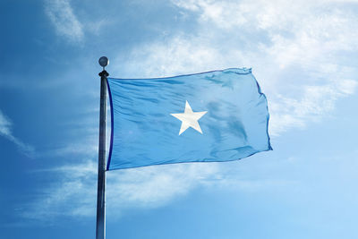 Low angle view of flag against blue sky