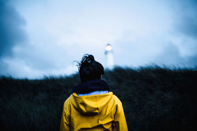 Rear view of woman standing by plants against sky