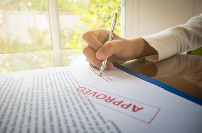 Cropped hand of woman signing on document