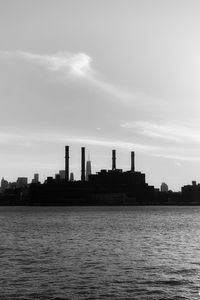 Factory by sea against sky in city