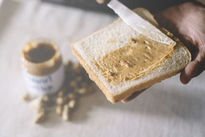 Close-up of person applying peanut butter on bread on table