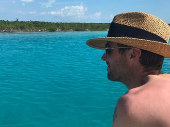 Side view of shirtless man wearing sunglasses by sea against sky