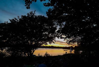 Silhouette trees by lake against sky during sunset