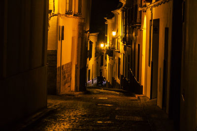 Illuminated street amidst buildings in city at night