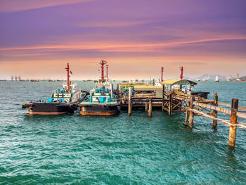 Ship moored at harbor against sky during sunset