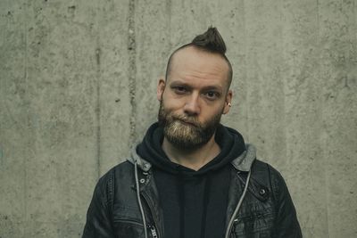 Portrait of man with spiky hair making face against wall