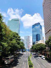 Cars on city street by buildings against sky