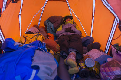 Young female hiker in warm clothing resting in tent