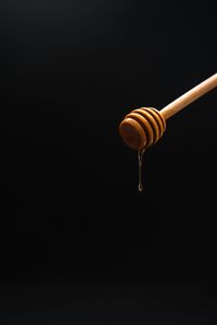 Close-up of honey on dipper against black background