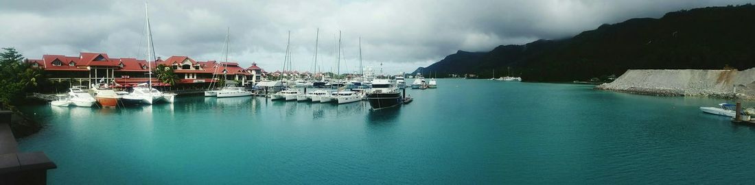 Boats in harbor against cloudy sky