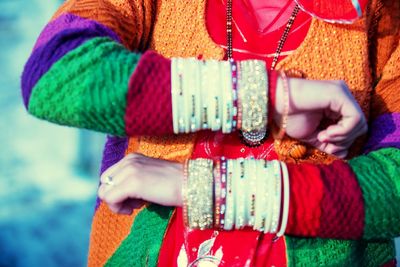 Midsection of woman wearing multi colored bangles