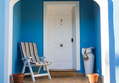 Empty chairs and table against blue wall of house