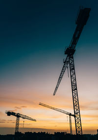 Low angle view of silhouette crane against sky during sunset