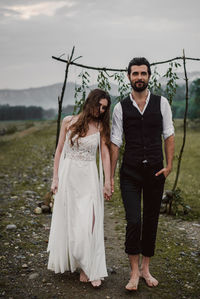 Full length of bride and bridegroom standing on field