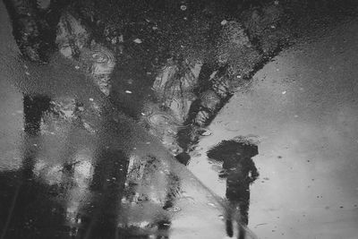 Reflection of person and eiffel tower in puddle during rainy season