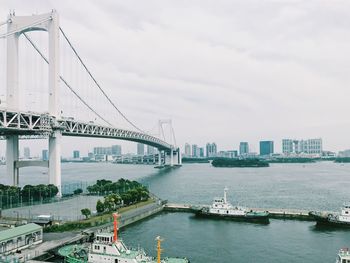 Bridge over river in city against sky