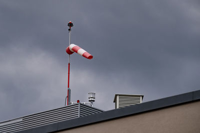Windsock on rooftop against cloud-sky