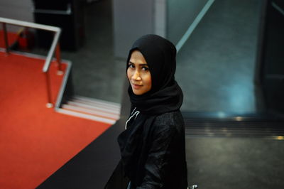 High angle portrait of woman in hijab standing on stairs