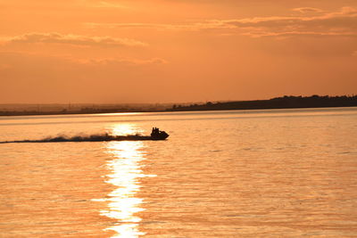 Silhouette boat in sea against sky during sunset