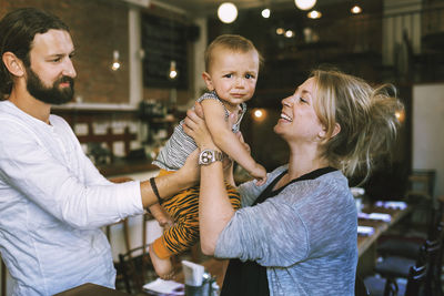 Happy mid adult parents with baby boy in restaurant