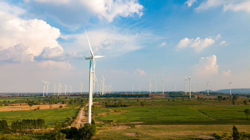 Scenic view of windmills on field against sky