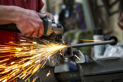 Midsection man grinding metal in factory