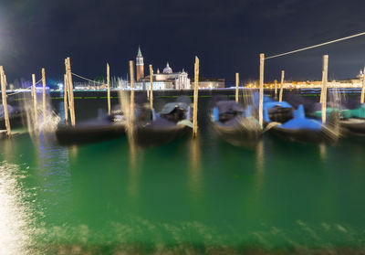 Boats moored in water at night