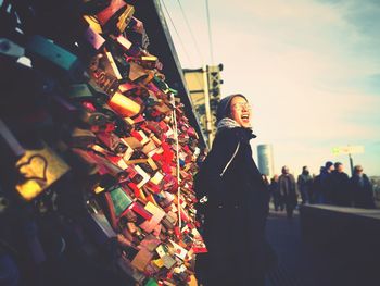 Woman standing by love locks on bridge
