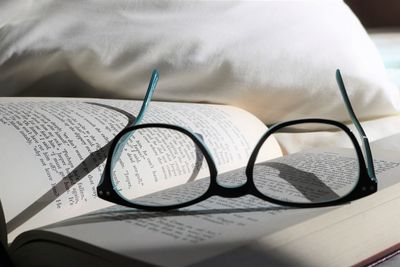 Close-up of reading glass on bed