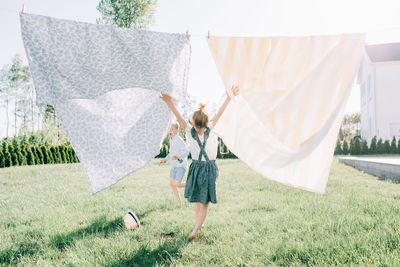 Young girl dancing through the washing on the line in summer