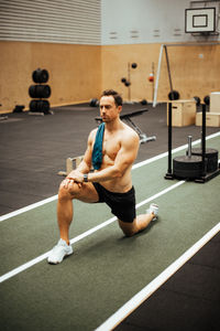 Full length of shirtless young man looking at camera