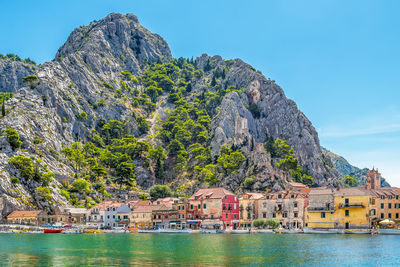 Buildings by sea against clear blue sky
