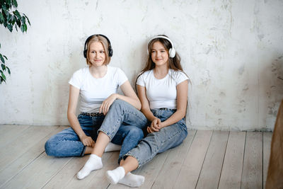 Portrait of young woman sitting against wall