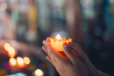 Cropped hand of woman holding illuminated candle