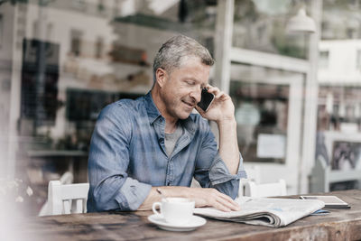 Mature man sitting in cafe talking on the phone